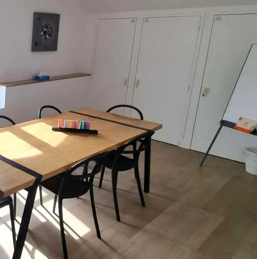 A cosy French language classroom in Caen with a wooden table, black chairs, and a whiteboard for immersive lessons