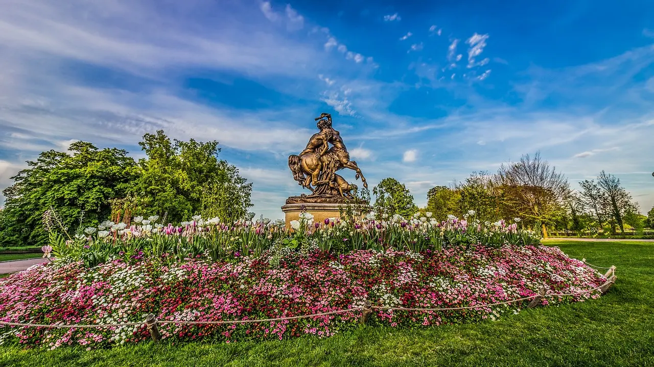 Bronze statue surrounded by vibrant spring flowers in Lyon’s Tête d’Or Park – Learn French in a peaceful natural setting