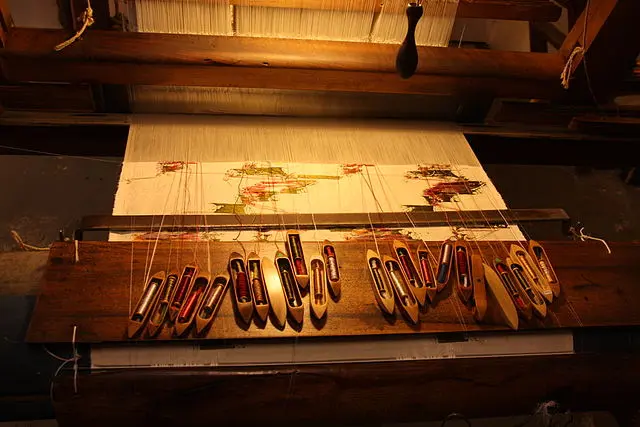 Close-up of a traditional Jacquard loom with shuttles and colored threads for tapestry weaving