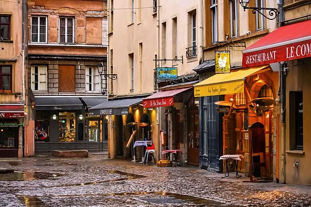 Cobbled street in Old Lyon with traditional bouchons and warm lights on a rainy day – perfect spot to discover French cuisine