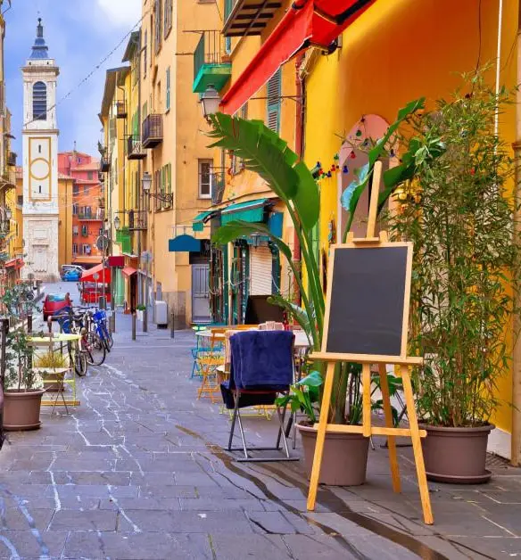 Colorful street with cafés and bell tower in the Old Town of Nice, France