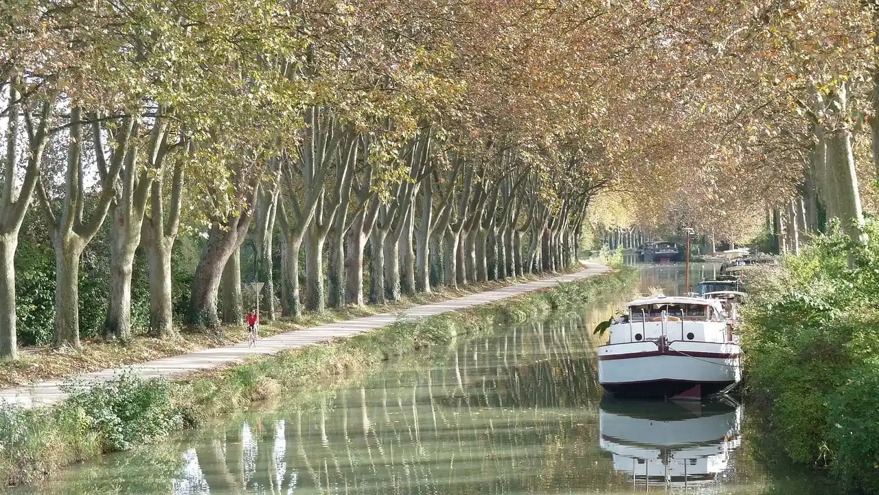 Cyclist and moored boat along the Canal du Midi near Montpellier in autumn