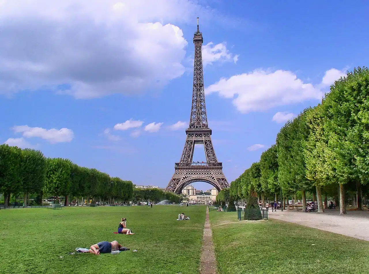 Eiffel Tower seen from the Champ de Mars on a sunny day with people relaxing on the grass