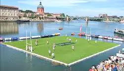 Floating rugby pitch on the Garonne River with players and spectators in Toulouse, France