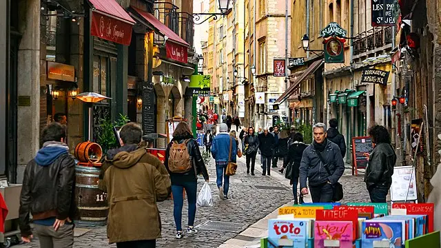 Pedestrians walking along a lively cobbled street in Old Lyon lined with restaurants, bookshops and boutiques