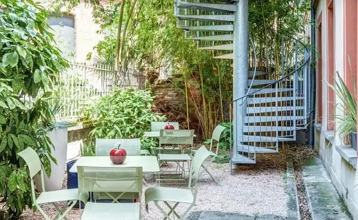 Quiet garden with green tables and spiral staircase at a French school in Toulouse