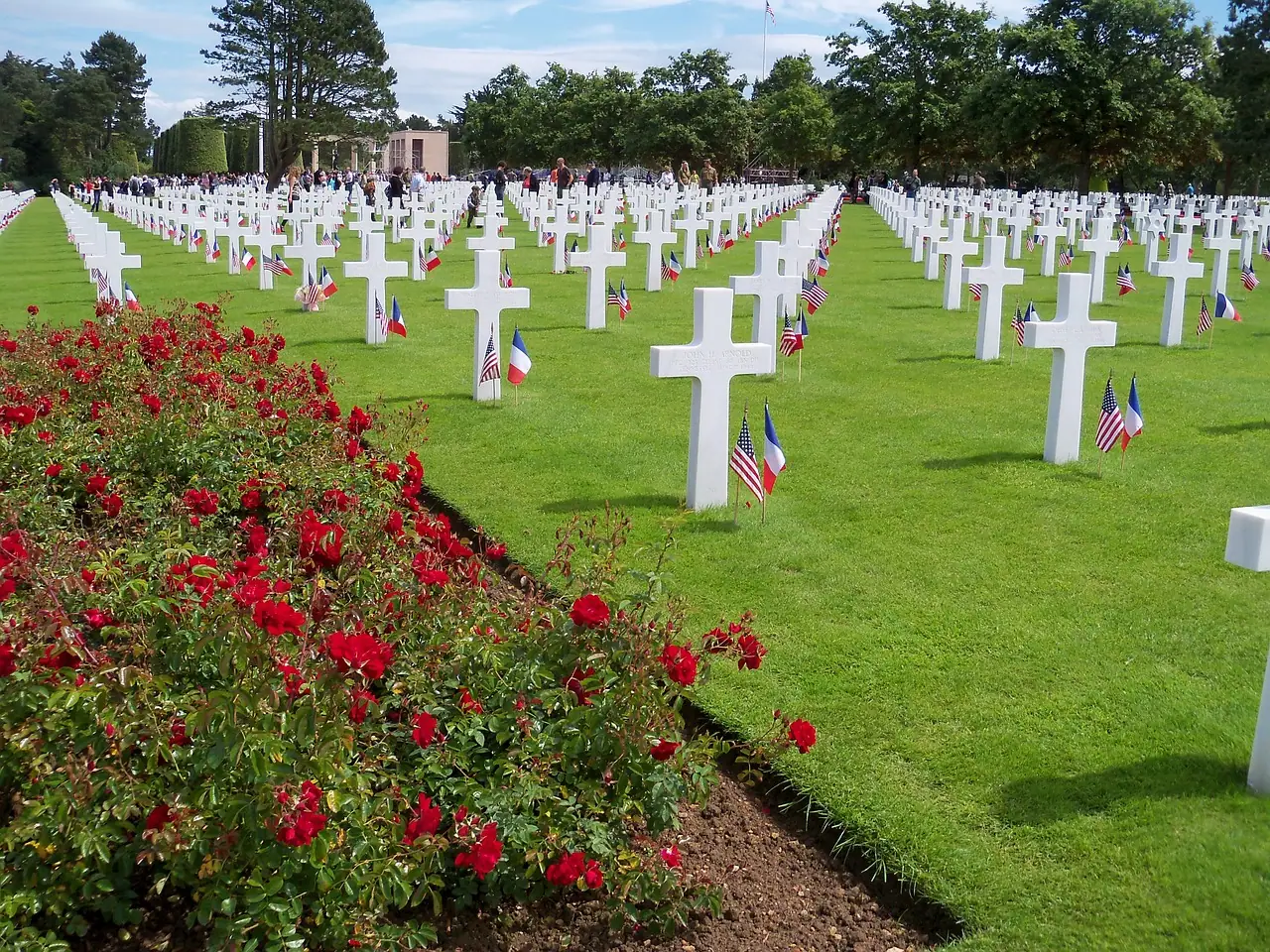 Rows of white crosses and American and French flags at the Normandy American Cemetery in Colleville-sur-Mer, France