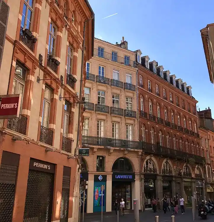 Traditional Toulouse architecture with shops and people walking in the city centre