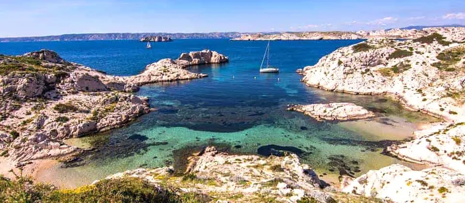 Turquoise cove with sailboat and rocky coastline on the Frioul Islands near Marseille, France