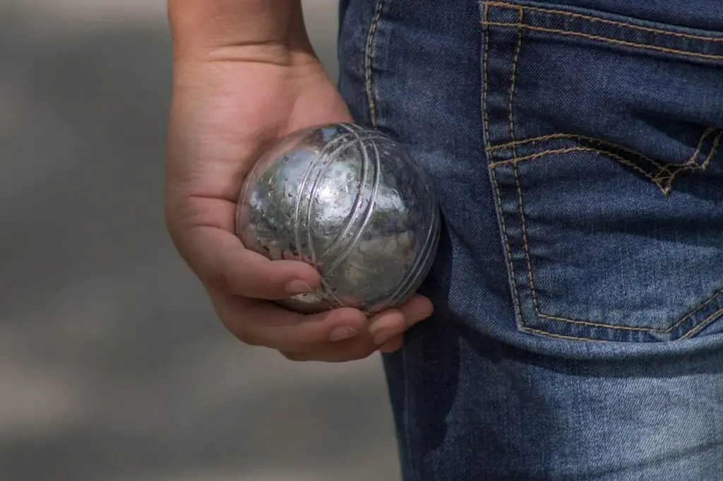 French language student holding a pétanque ball during a cultural activity in Montpellier