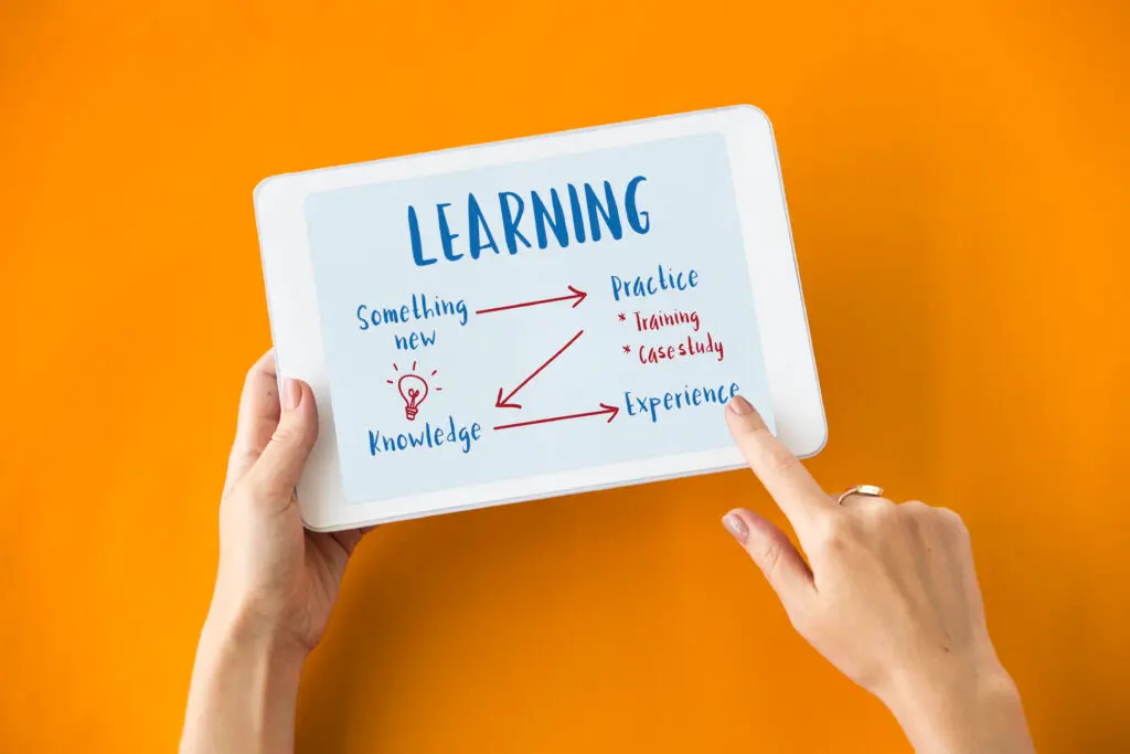Hands holding tablet with the word “Learning” – Learn French online from anywhere