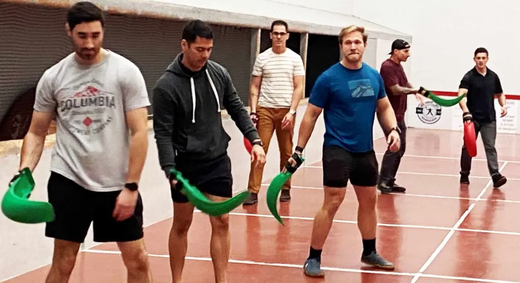 Men learning pelote basque on an indoor court in Bordeaux