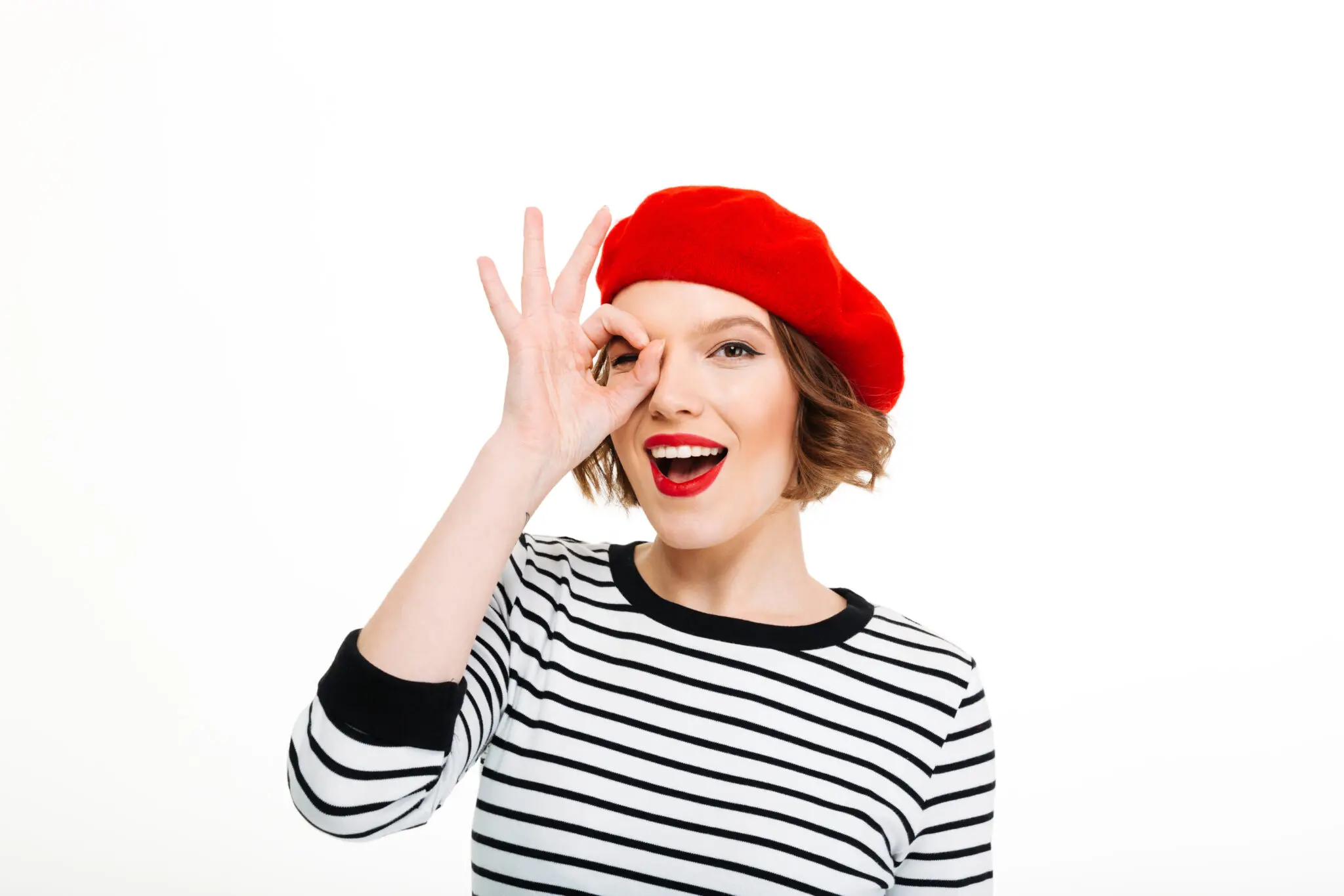 Smiling woman wearing red beret and striped shirt making an OK sign – Learn French online with a Parisian touch